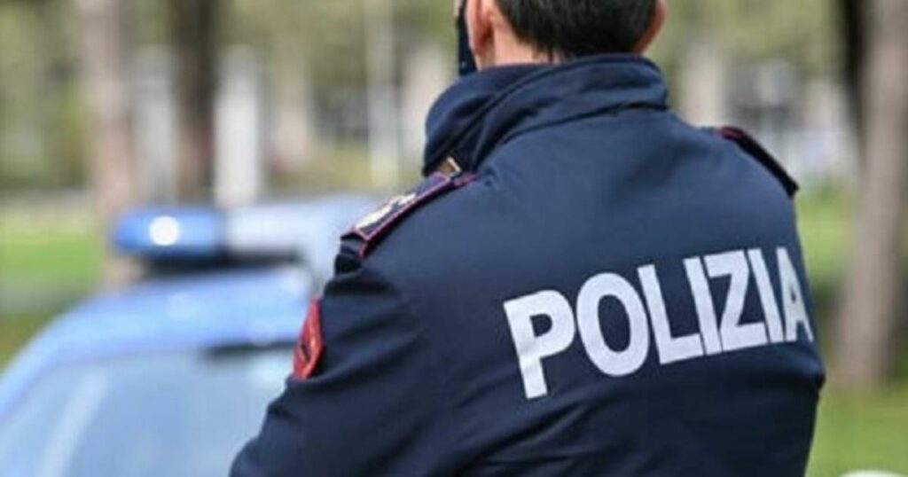 Un agente della Polizia di Stato con sullo sfondo una pattuglia