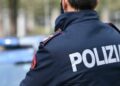 Un agente della Polizia di Stato con sullo sfondo una pattuglia
