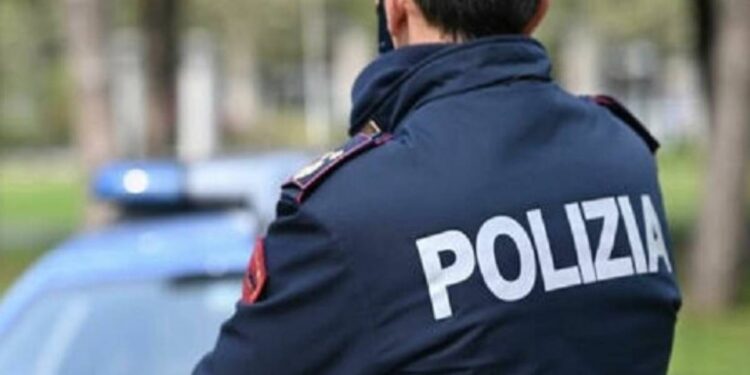 Un agente della Polizia di Stato con sullo sfondo una pattuglia