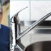 Il sindaco di Vibo Valentia, Enzo Romeo, e un rubinetto con l'acqua corrente
