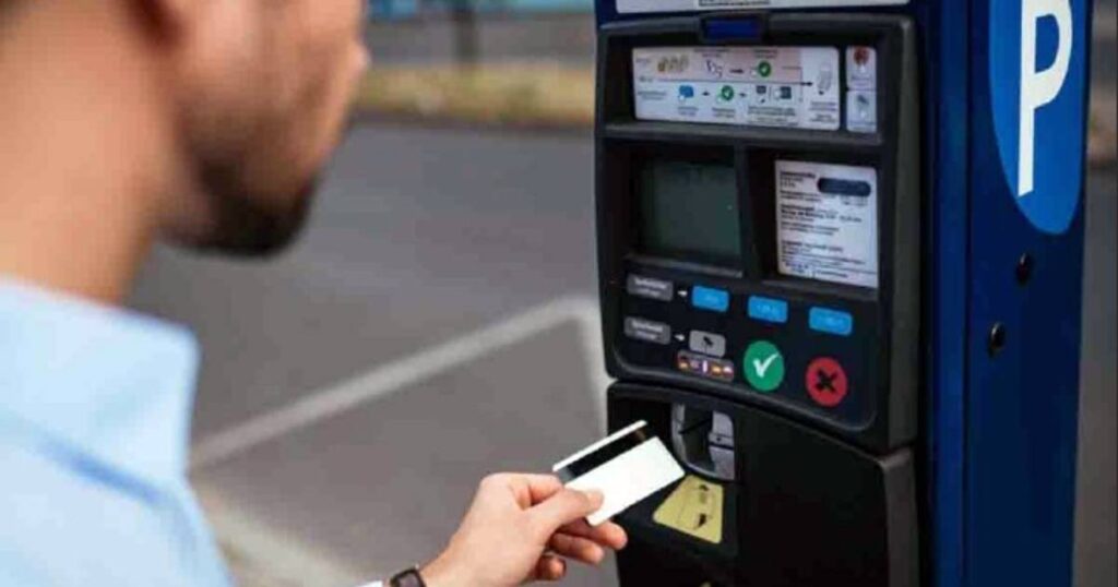 Un uomo intento a pagare presso un parcometro il parcheggio delimitato dalle strisce blu