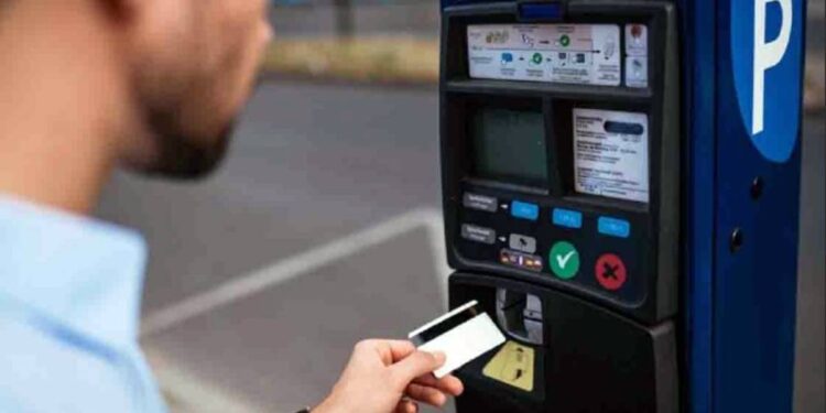 Un uomo intento a pagare presso un parcometro il parcheggio delimitato dalle strisce blu