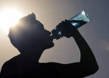 Un uomo si idrata sotto il sole durante una calda giornata