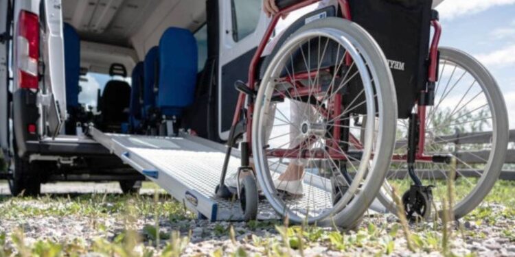 Una sedia a rotelle ed un mezzo adibito al trasporto per le persone con disabilità