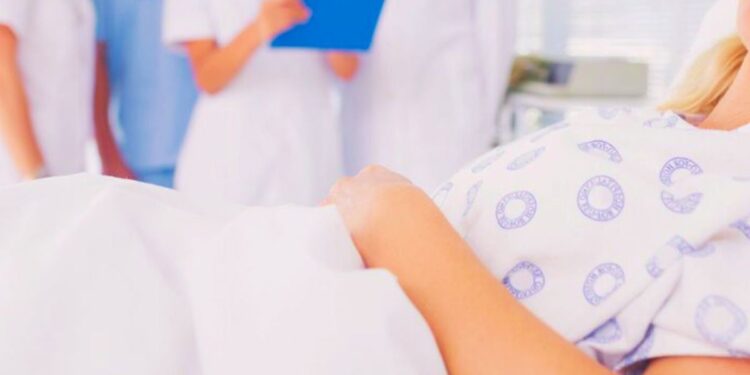 Un paziente ricoverato in ospedale con sullo sfondo dei medici