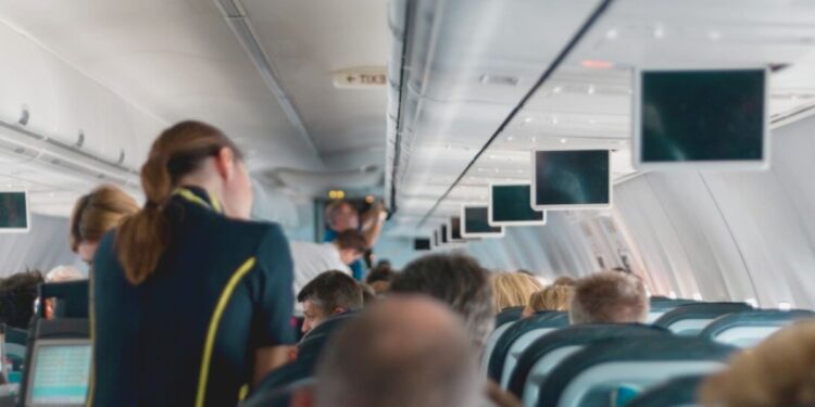 L'interno di un aereo con una hostess e i passeggeri