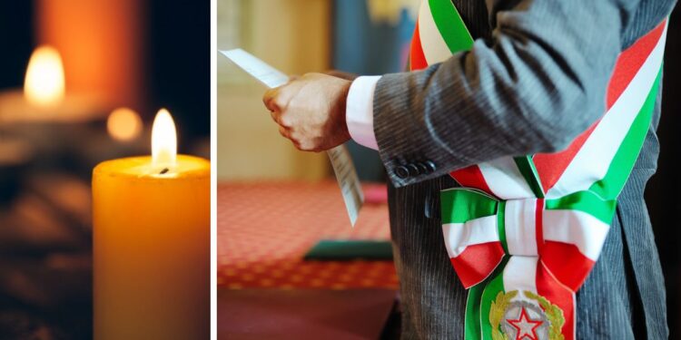 Un sindaco con la fascia tricolore e delle candele a lutto