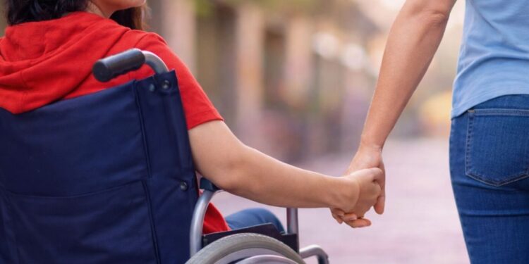 Una madre con una figlia disabile in sedia a rotelle