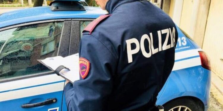 Un poliziotto, un agente della Polizia di Stato, accanto ad una volante