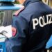 Un poliziotto, un agente della Polizia di Stato, accanto ad una volante