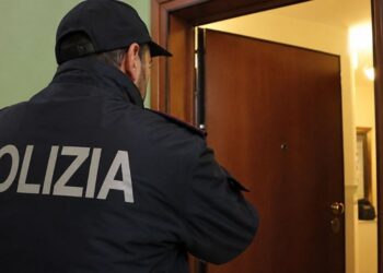 Un agente di Polizia di fronte alla porta di una abitazione