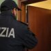 Un agente di Polizia di fronte alla porta di una abitazione