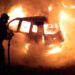 I vigili del fuoco cercano di spegnere un'auto data alle fiamme