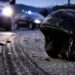 Un casco sull'asfalto dopo un incidente con sullo sfondo i mezzi di soccorso