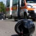 Un casco sull'asfalto e una ambulanza sul luogo di un incidente