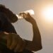 Una persona beve acqua durante una intensa giornata di caldo in estate