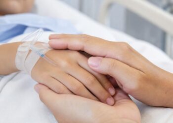 Un bambino ricoverato in ospedale, mano nella mano