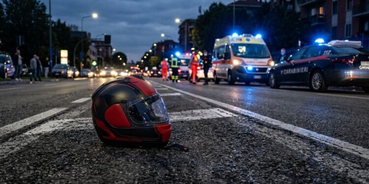 Un casco sull'asfalto a seguito di un incidente stradale. Sullo sfondo ambulanza e carabinieri