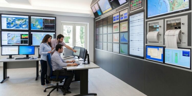 Una control room per i terremoti con studiosi intenti a controllare i sismografi e i dati