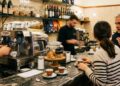 Un bar con clienti al bancone e baristi