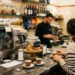 Un bar con clienti al bancone e baristi